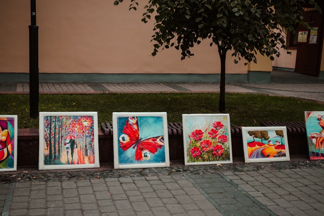Photo by Daniil Yakovchik a row of paintings sitting on the side of a road